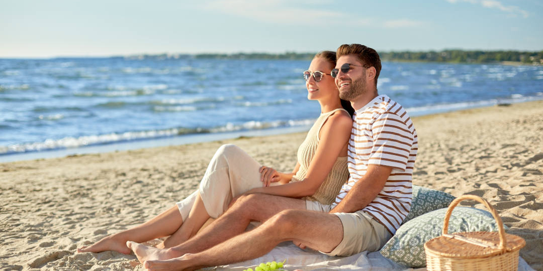 Happy couple having picnic on summer beach - deposit photos 506521620