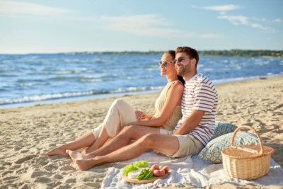 Happy couple having picnic on summer beach - deposit photos 506521620