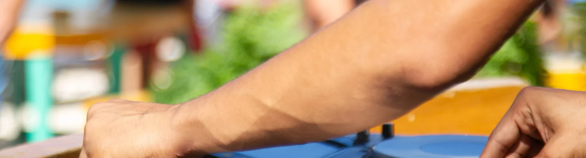 DJ mixing music at a vibrant beach club with ocean and crowd in background